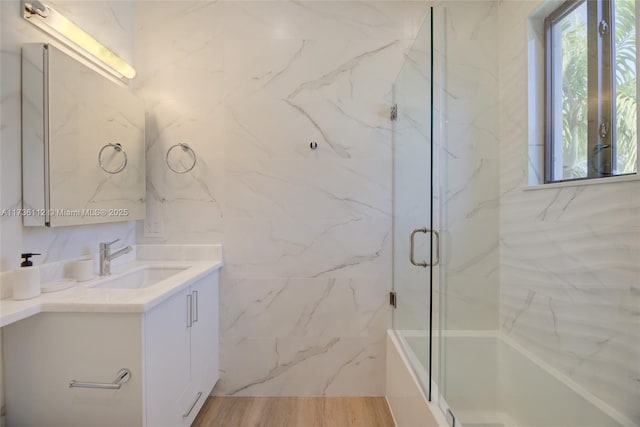 full bath featuring tile walls, wood finished floors, vanity, and an enclosed shower