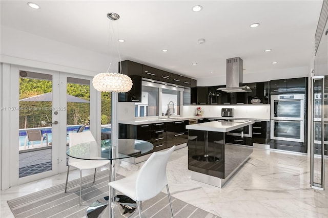 1251 Kane Concourse, Bay Harbor Islands, FL 33154 - kitchen with island exhaust hood, stainless steel double oven, dark cabinetry, a kitchen island, and light countertops