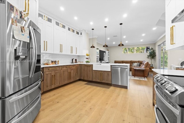 kitchen featuring white cabinetry, decorative light fixtures, stainless steel appliances, light hardwood / wood-style floors, and decorative backsplash