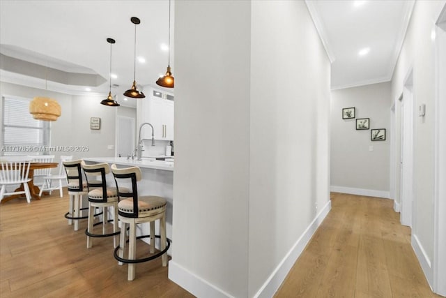 hallway with ornamental molding, sink, and light wood-type flooring