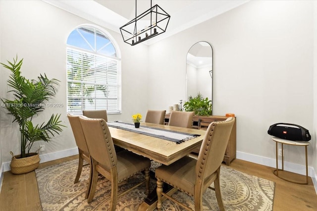 dining room with hardwood / wood-style flooring, ornamental molding, and an inviting chandelier