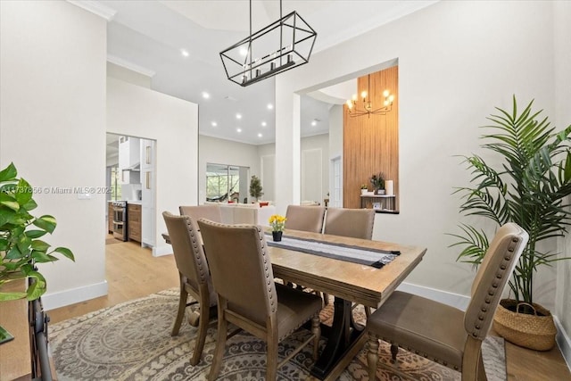 dining space with ornamental molding, an inviting chandelier, and light hardwood / wood-style floors