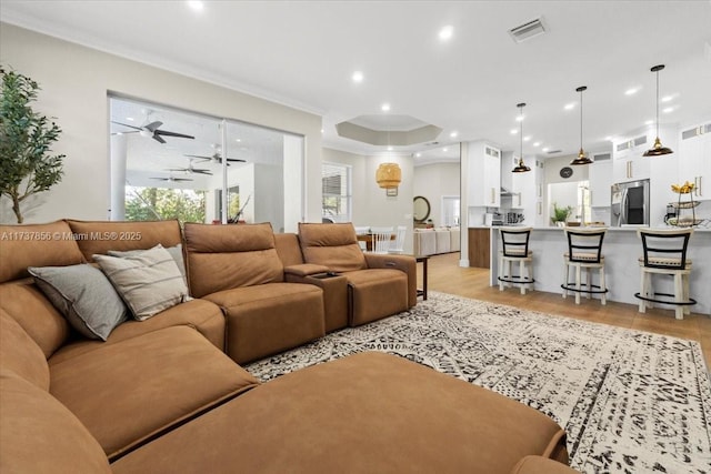 living room with ornamental molding, ceiling fan, and light wood-type flooring