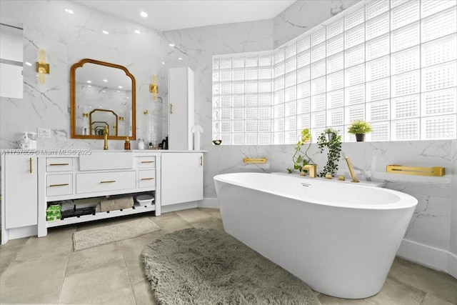 bathroom featuring a bathing tub, plenty of natural light, tile walls, and vanity