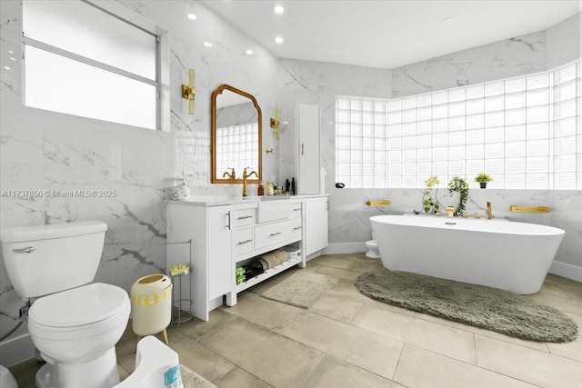 bathroom with a tub to relax in, vanity, toilet, and tile walls