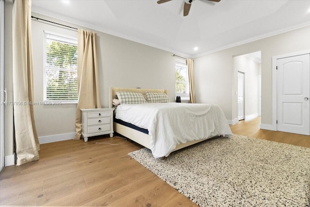 bedroom with crown molding, ceiling fan, a tray ceiling, and light hardwood / wood-style flooring