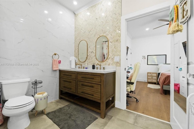 bathroom with tile patterned floors, vanity, toilet, and tile walls