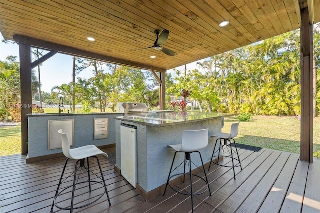 wooden terrace featuring a grill, ceiling fan, and an outdoor wet bar