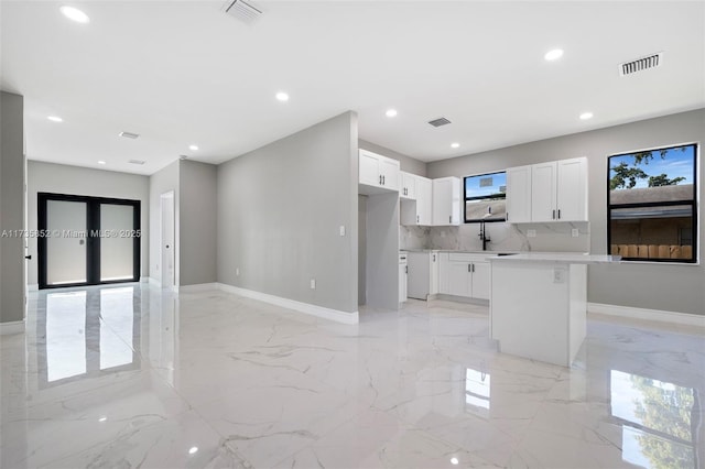 kitchen featuring white cabinetry, tasteful backsplash, a healthy amount of sunlight, and a kitchen island