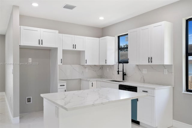 kitchen with white cabinetry, a kitchen island, and sink