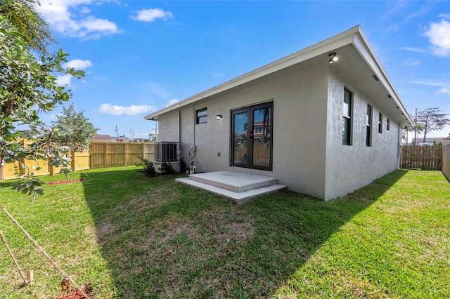 back of property with central AC unit and a lawn