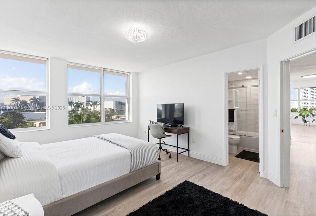 bedroom featuring light wood-type flooring and ensuite bath