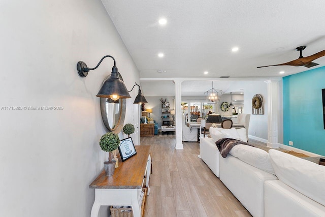 living room featuring decorative columns, light hardwood / wood-style floors, and ceiling fan