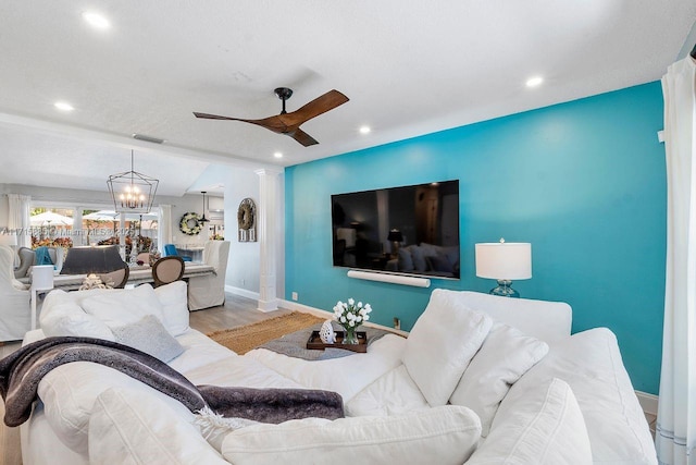 living room featuring hardwood / wood-style floors, ceiling fan with notable chandelier, and decorative columns