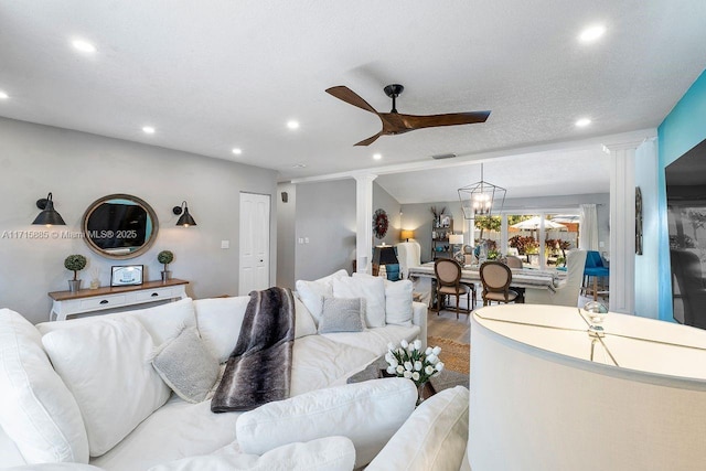 living room with decorative columns, wood-type flooring, and ceiling fan