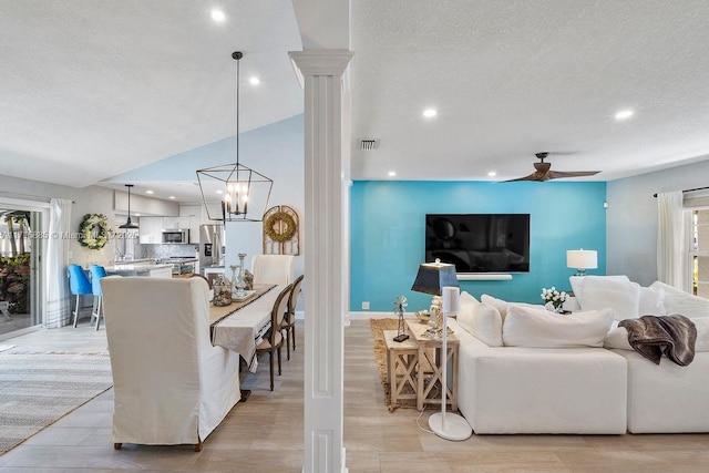 living room with decorative columns, ceiling fan, a textured ceiling, and light hardwood / wood-style floors