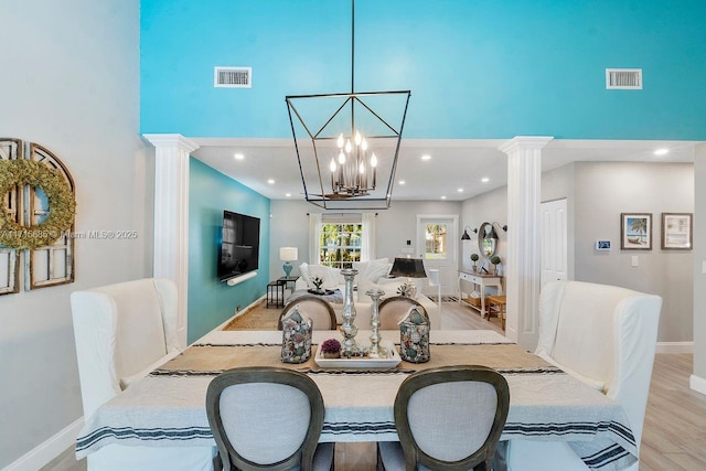 dining room featuring decorative columns, a high ceiling, and light hardwood / wood-style floors