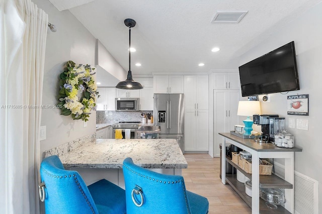 kitchen with white cabinetry, hanging light fixtures, light stone counters, kitchen peninsula, and stainless steel appliances