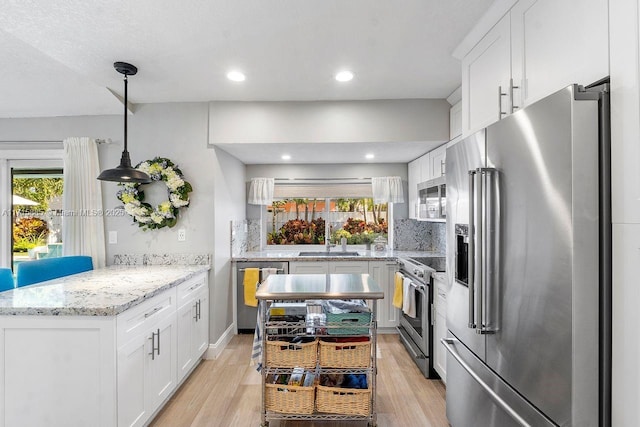 kitchen featuring white cabinetry, appliances with stainless steel finishes, sink, and hanging light fixtures