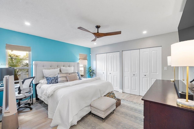 bedroom with multiple closets, ceiling fan, and light wood-type flooring