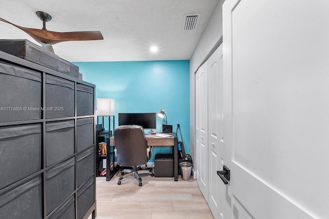 home office with light hardwood / wood-style flooring and a textured ceiling