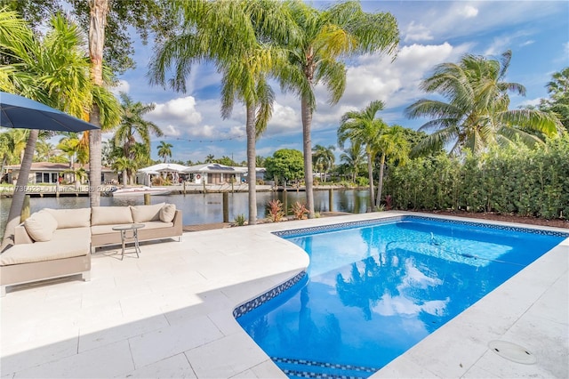 view of pool with an outdoor living space, a water view, and a patio area