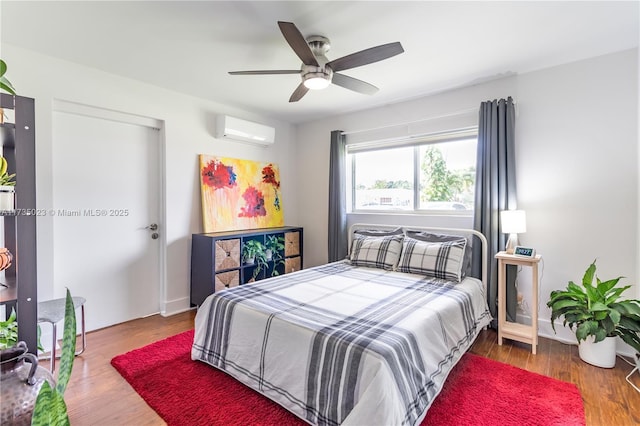 bedroom with ceiling fan, wood-type flooring, and a wall unit AC