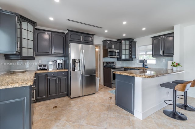 kitchen featuring light tile patterned flooring, tasteful backsplash, sink, kitchen peninsula, and stainless steel appliances