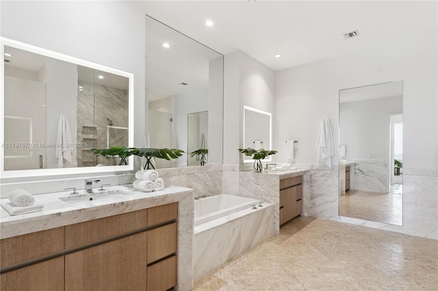 bathroom featuring tile walls, vanity, and shower with separate bathtub