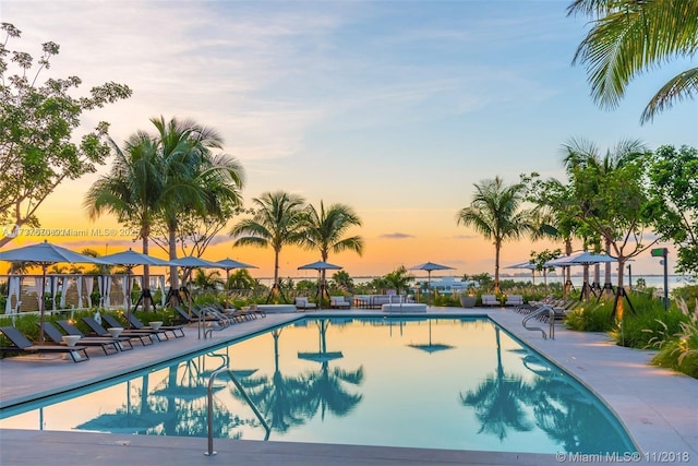 pool at dusk with a patio area