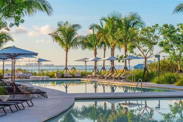 view of swimming pool featuring a water view and a patio