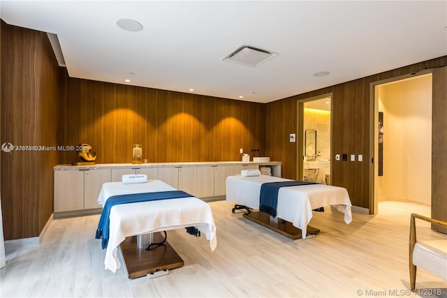 bedroom featuring light wood-type flooring and wood walls