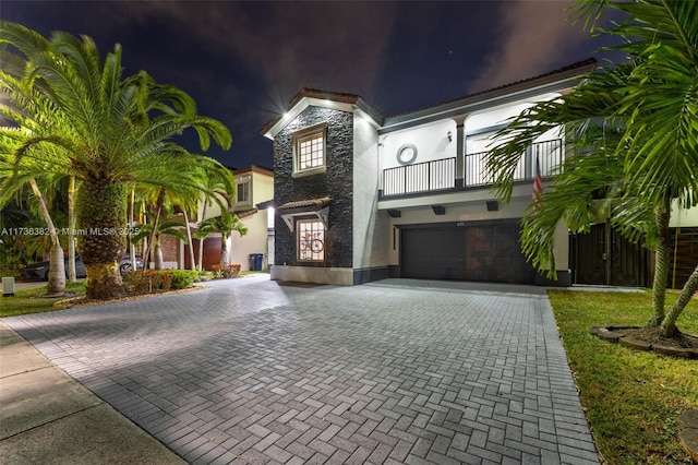 view of front of home featuring a garage, a balcony, and central AC unit