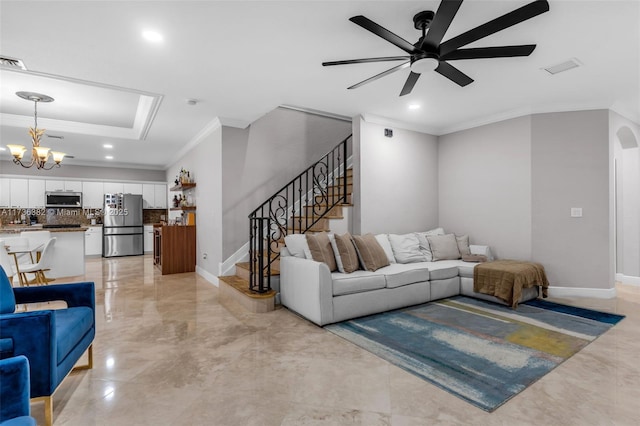 living room featuring a tray ceiling, ceiling fan with notable chandelier, and ornamental molding