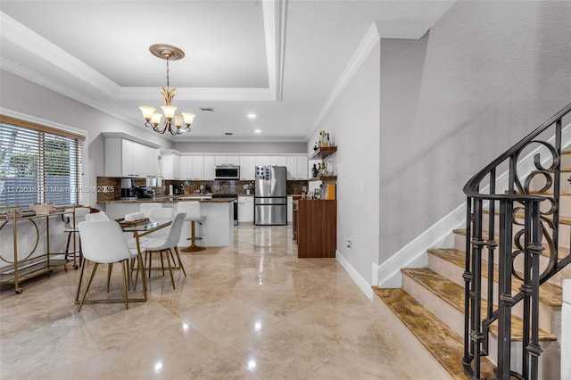 kitchen featuring a raised ceiling, white cabinetry, backsplash, kitchen peninsula, and stainless steel appliances