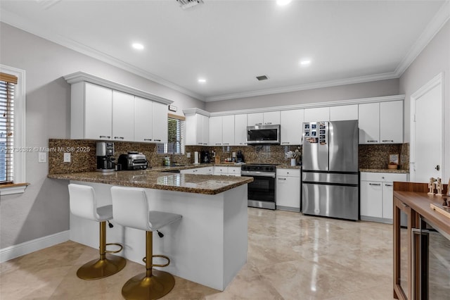 kitchen featuring white cabinets, dark stone counters, ornamental molding, kitchen peninsula, and stainless steel appliances