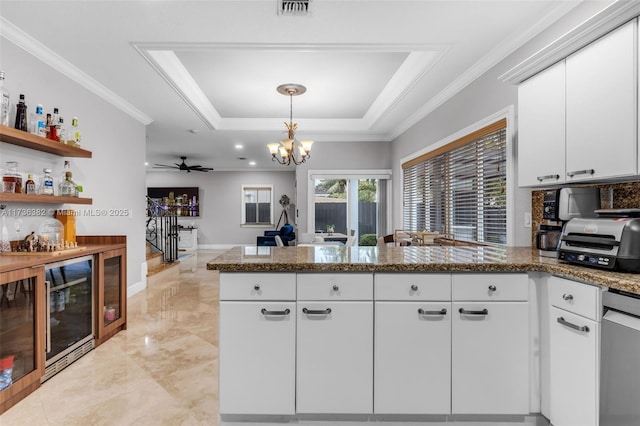 kitchen with a tray ceiling, white cabinets, and kitchen peninsula