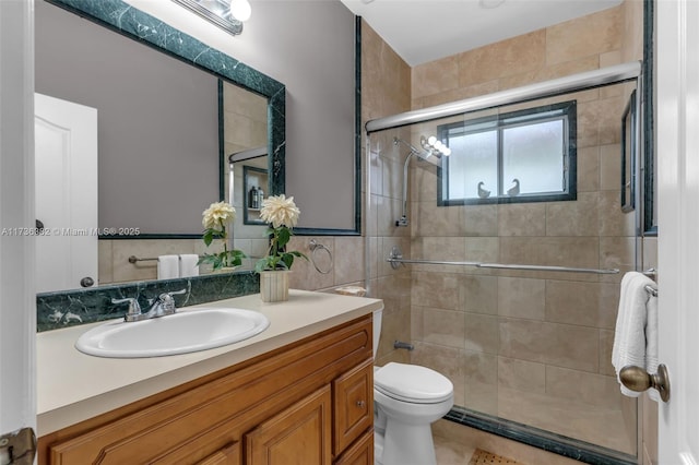 bathroom with walk in shower, vanity, toilet, and tile walls