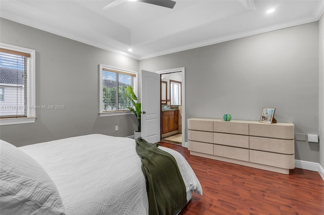 bedroom featuring dark hardwood / wood-style floors, ceiling fan, a raised ceiling, crown molding, and ensuite bath