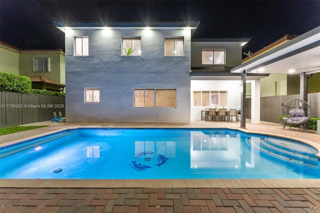 pool at night featuring a patio