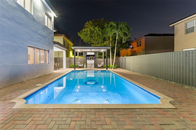 pool at night featuring a patio