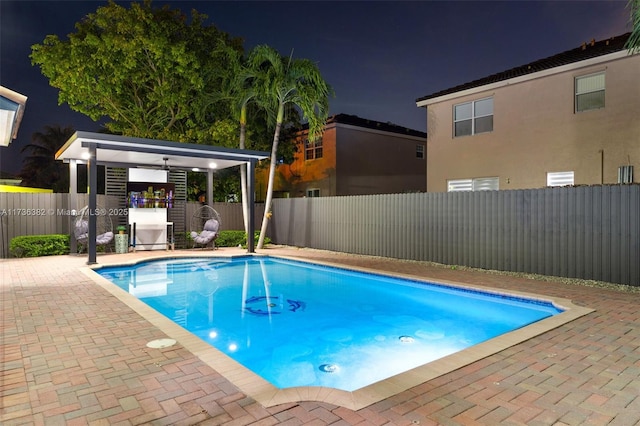 pool at twilight with a patio area