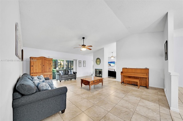 living room featuring lofted ceiling, light tile patterned floors, ceiling fan, a large fireplace, and a textured ceiling