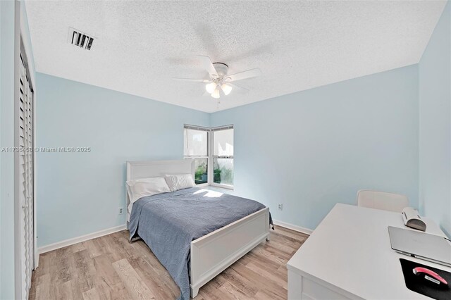 bedroom featuring ceiling fan, a textured ceiling, and light wood-type flooring