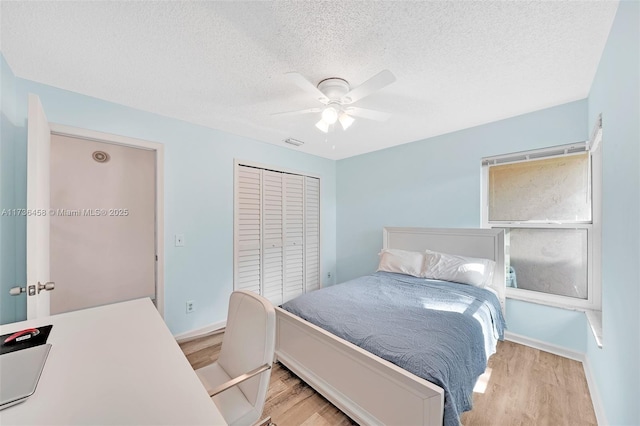 bedroom featuring ceiling fan, a closet, light hardwood / wood-style floors, and a textured ceiling