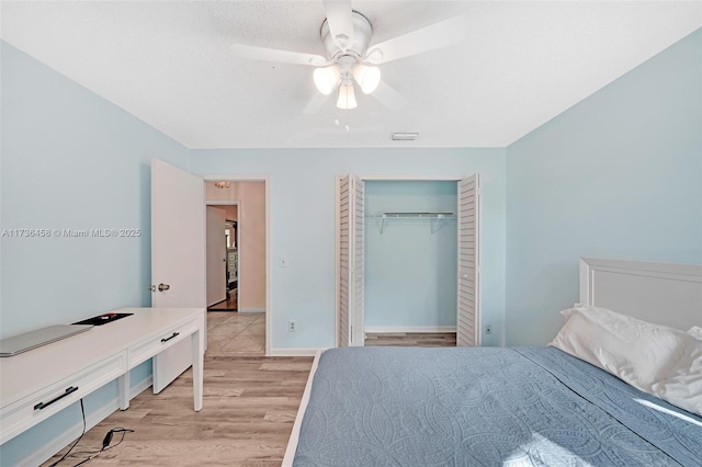 bedroom featuring ceiling fan, a textured ceiling, light hardwood / wood-style floors, and a closet