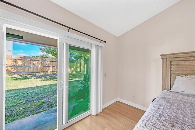 bedroom featuring lofted ceiling, access to outside, and light hardwood / wood-style floors