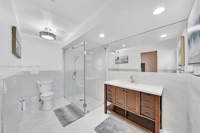 bathroom with tile walls, vanity, an enclosed shower, tile patterned floors, and toilet