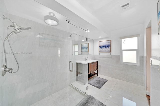 bathroom featuring vanity, tile walls, tile patterned floors, and a shower with shower door