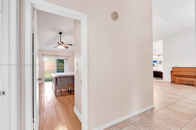 hallway with lofted ceiling and light tile patterned floors